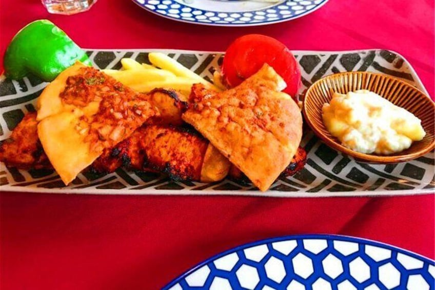 Un plato de pollo a la parrilla, pan plano y una guarnición de arroz. 4