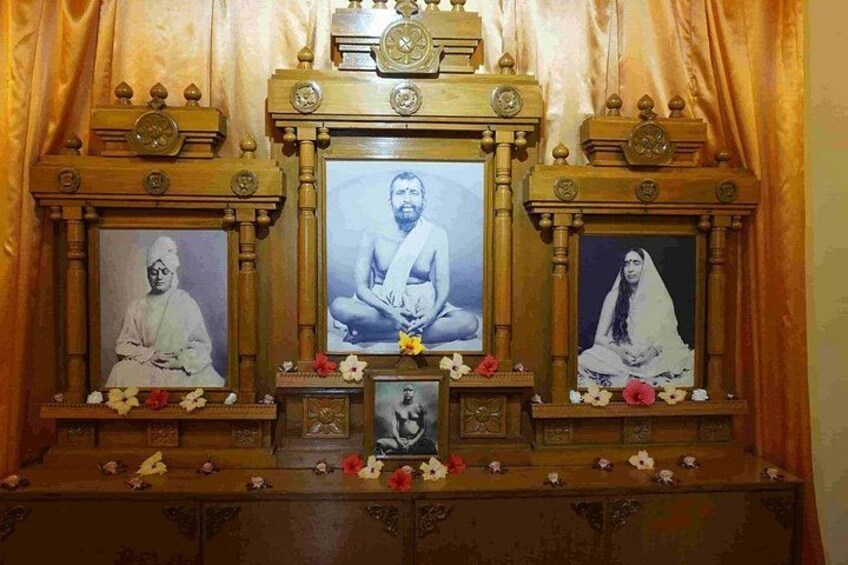 Un santuario con tres fotografías enmarcadas, una figura central para la meditación y una estatua de perro pequeño. 2