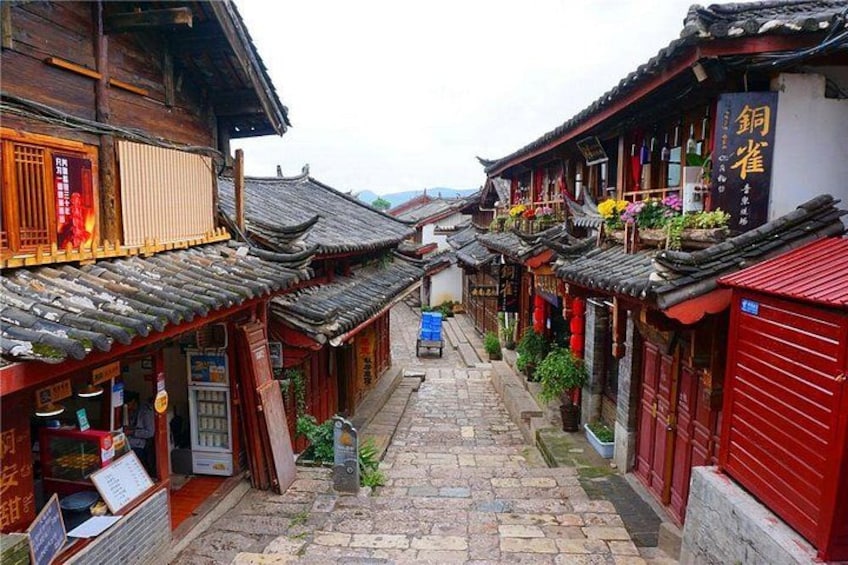 A narrow alley with traditional wooden buildings, tiled roofs, and red doors. 5
