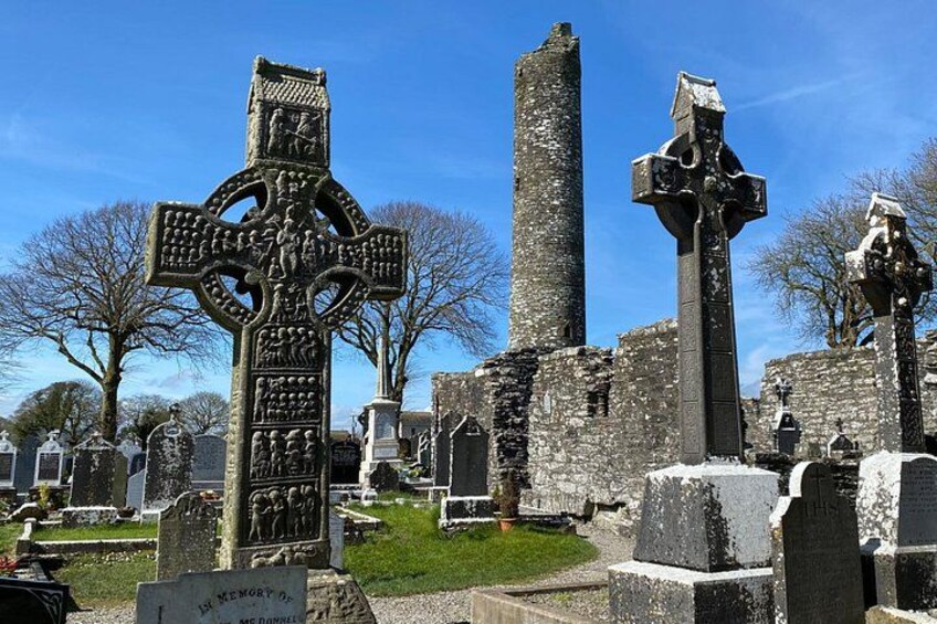 A cemetery with ancient crosses and a tall stone tower. 4