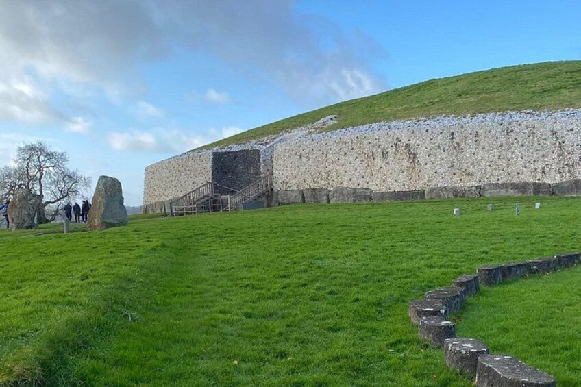 A stone wall, grassy field, and a hill. 3