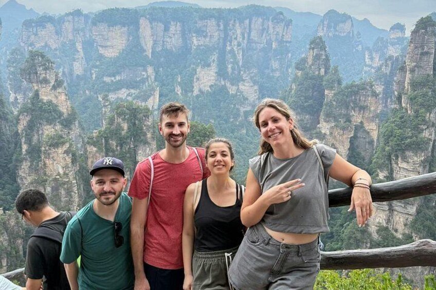 A group of people standing on a viewing platform with a mountainous landscape in the background. 3