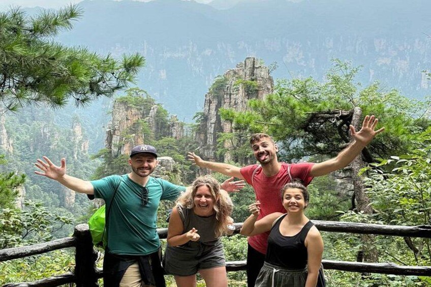 A group of people standing on a wooden platform with a mountainous landscape in the background. 3