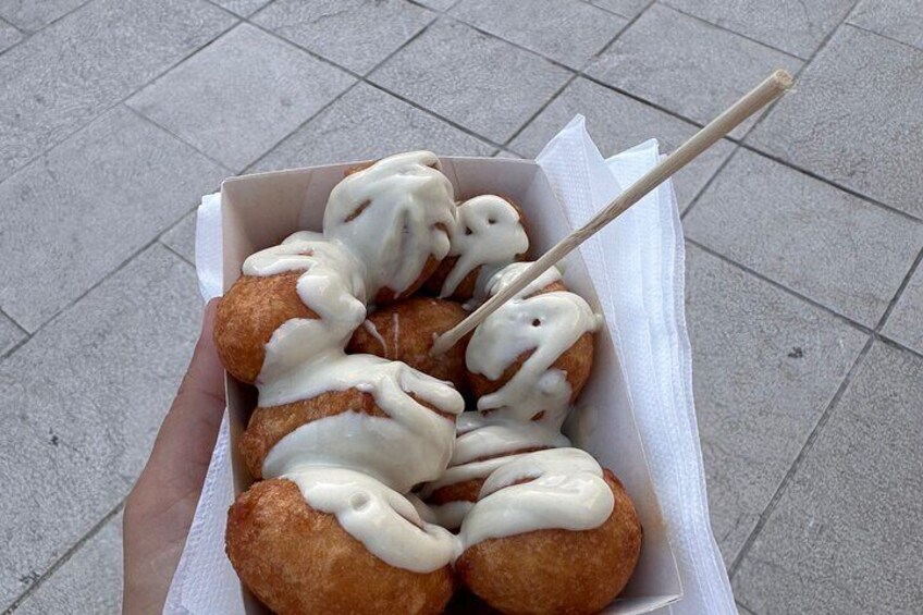 A box of doughnuts with white icing and a chopstick. 4