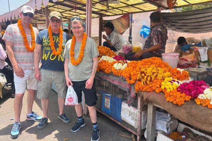 A market stall with colorful flowers and a group of people standing in front. 2