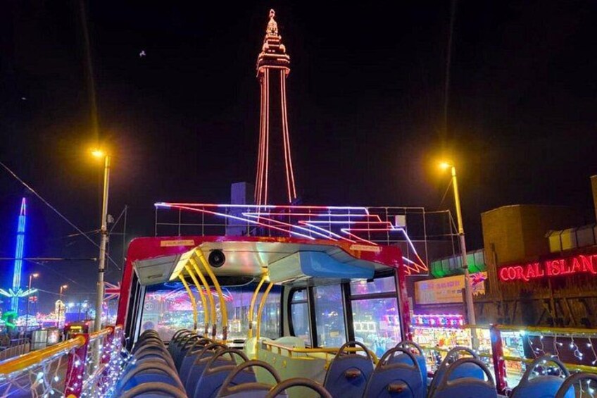 A brightly lit Ferris wheel, a tall tower, and a bus with neon lights. 4