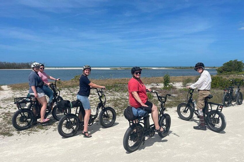 Four people on bicycles near a body of water. 3