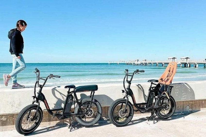 Una playa con dos bicicletas y una persona caminando. 2