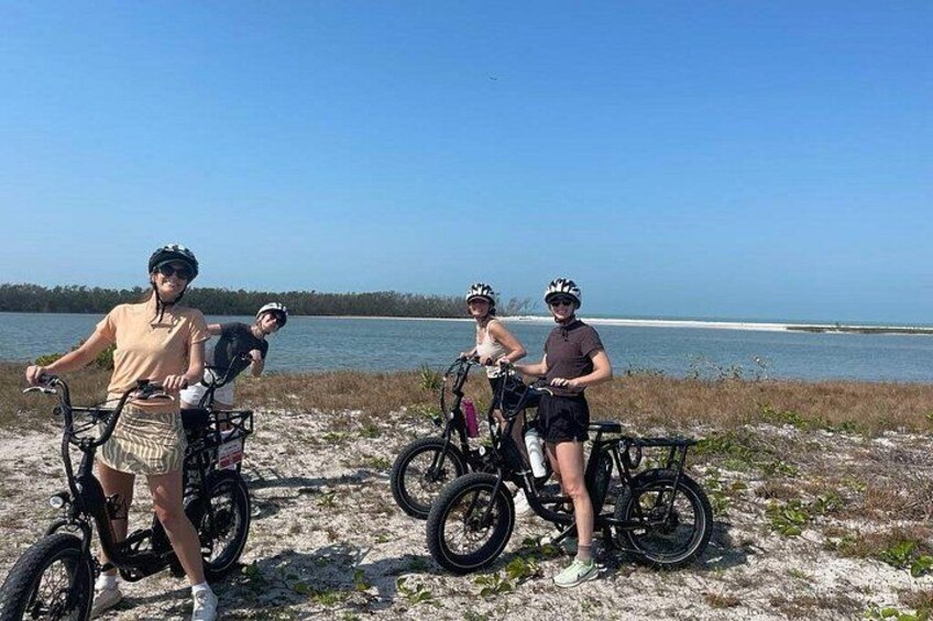 Three people on bicycles by a lake with a clear sky. 4