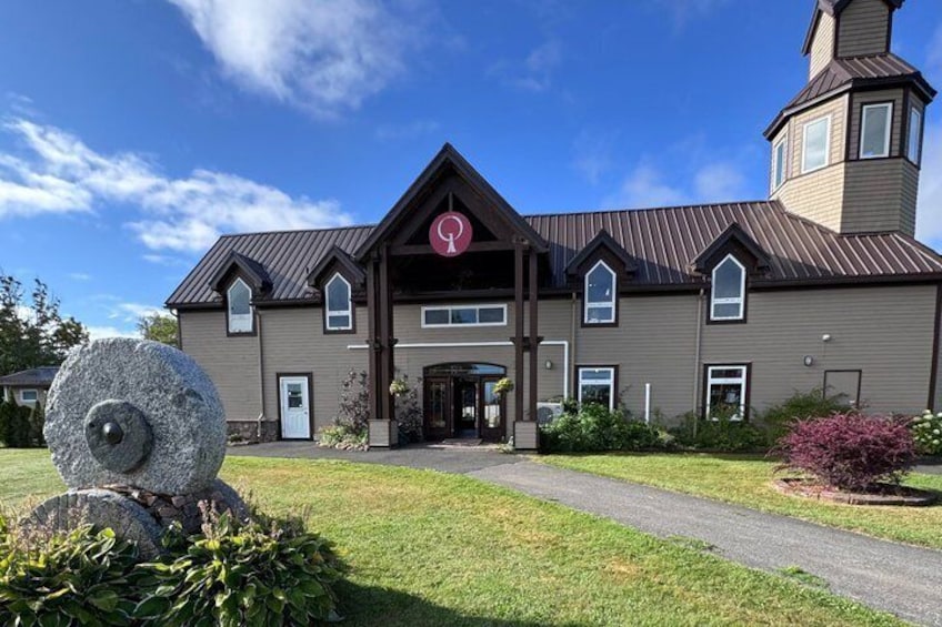 A large building with a prominent entrance, a stone sculpture, and a well-maintained lawn. 2