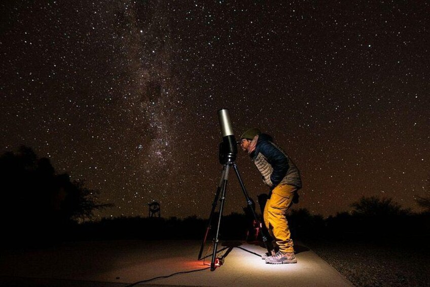 A person using a telescope under a starry night sky. 5