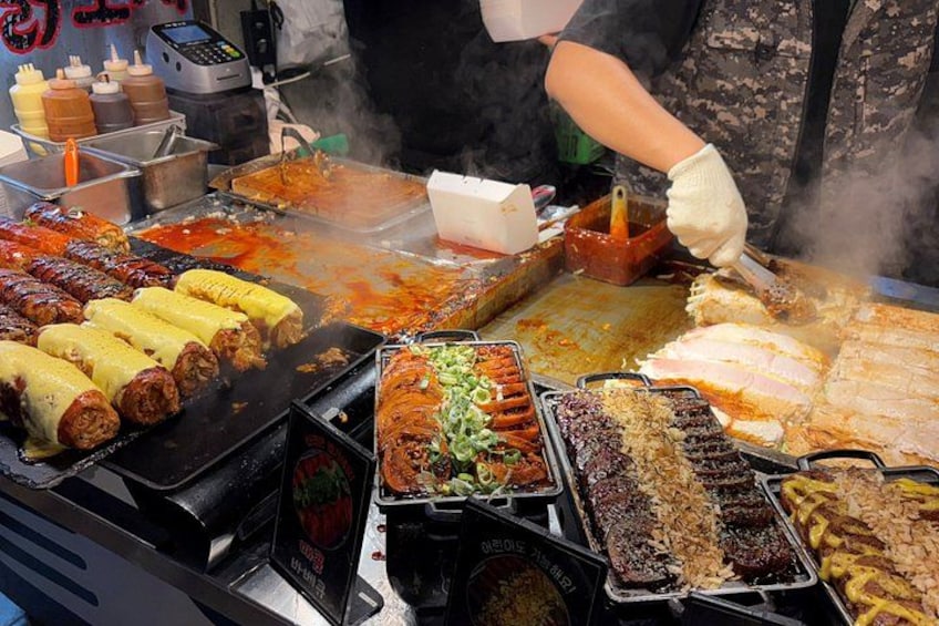 A street food stall with grilled meats, vegetables, and sauces. 3