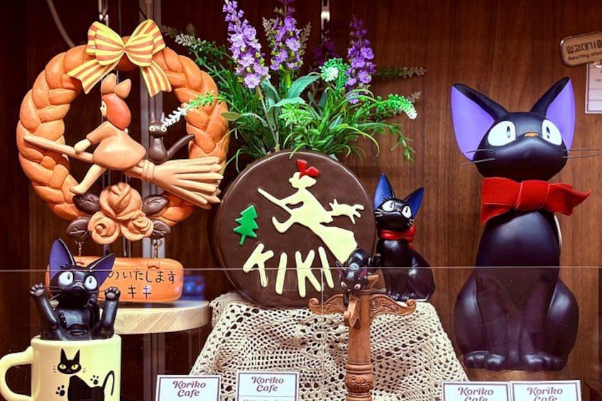 A display with a wreath, a sign with Japanese characters, and two cat statues. 4