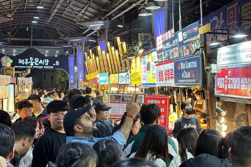 A crowded indoor market with various food stalls and signs in a foreign language. 5