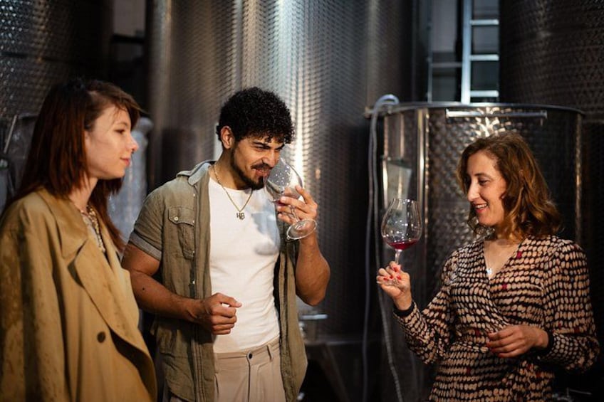 Three people in a wine cellar holding wine glasses. 2