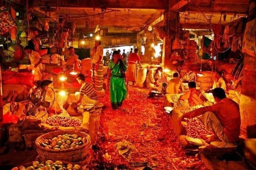 Un mercado bullicioso con gente comprando y vendiendo productos, cestas de frutas y una mujer con un vestido verde. 2