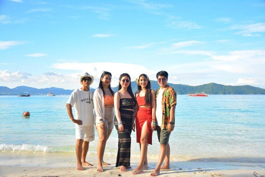 A group of people standing on a beach with a clear sky and calm sea in the background. 3