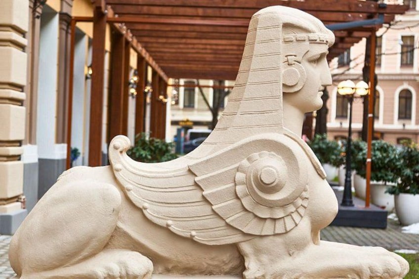A stone sphinx statue in an outdoor setting with architectural elements in the background. 5