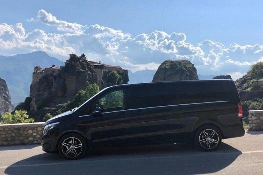 A black van parked on a road with a mountainous landscape in the background. 2