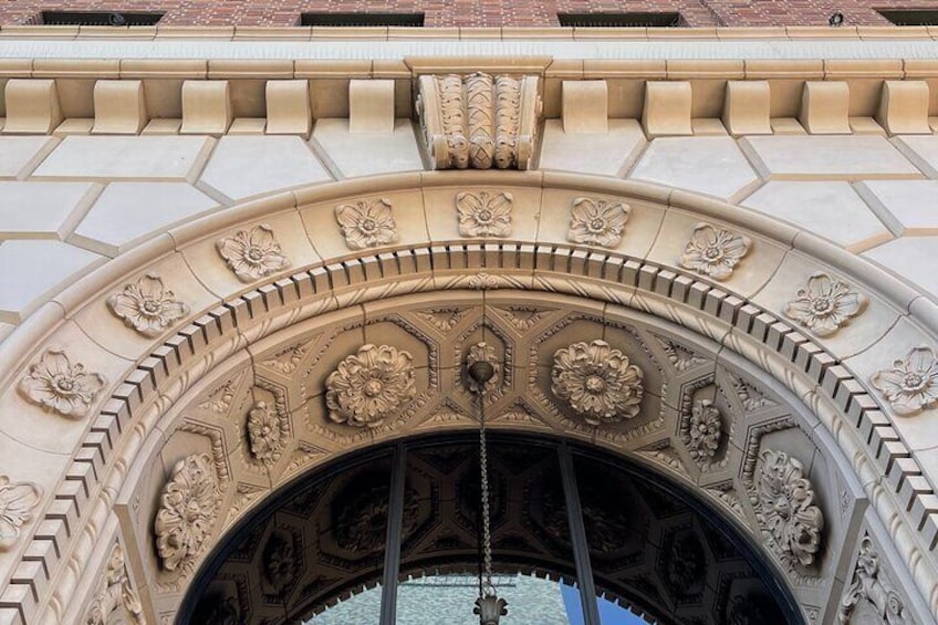 An ornate stone archway with floral carvings and a hanging chain. 4