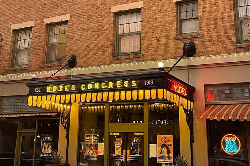 A historic building with a marquee sign reading 'Hotel Congress' and neon lights. 2