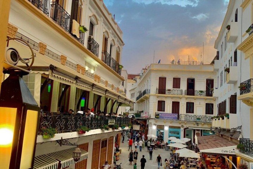 A bustling street with cafes and shops, pedestrians, and a mix of architectural styles. 2
