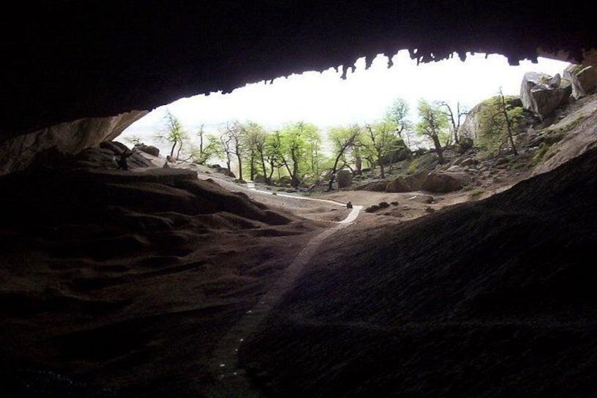 A cave entrance with a rocky interior and a view of trees outside. 2