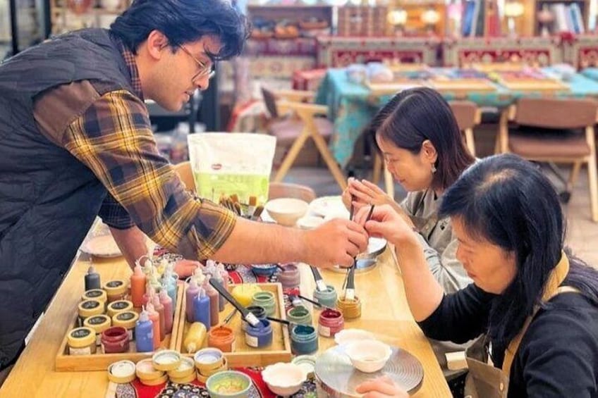 Una persona pintando con pinceles y pinturas sobre una mesa. 2