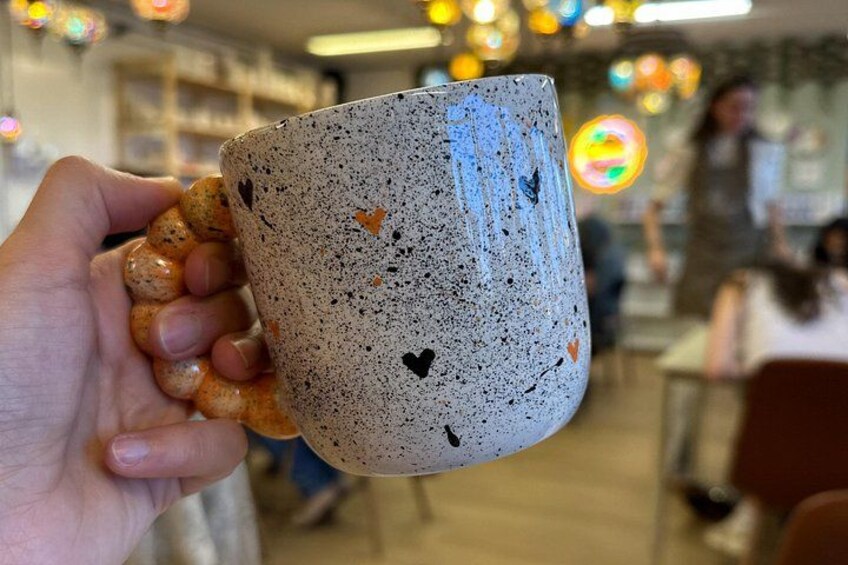 A hand holding a speckled ceramic mug with a handle. 3