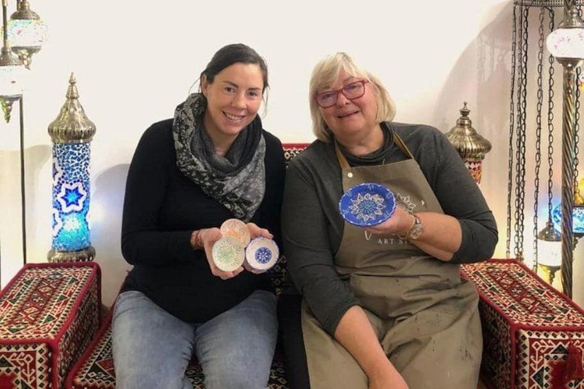 Twee personen zitten op een gestreept bankje, decoratieve lampen op de achtergrond. 2