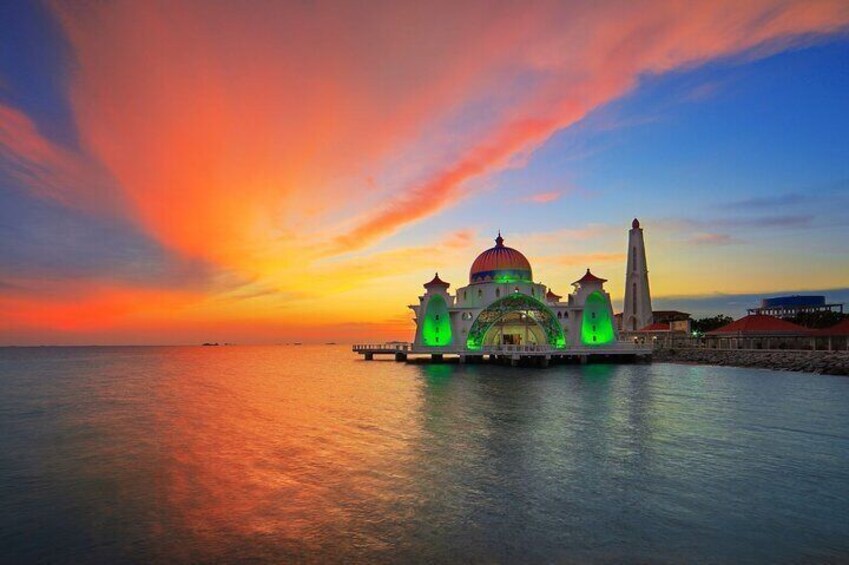 A mosque with a dome and minarets, illuminated by green lights, at sunset. 3