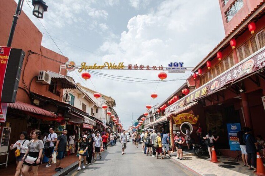 A bustling street with shops and red lanterns, a sign for 'Joy LED Media AV', and people walking and standing. 1