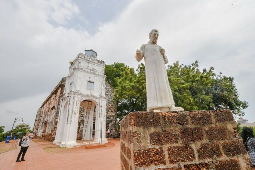A historical building with an arched entrance and a statue of a man on a pedestal. 2