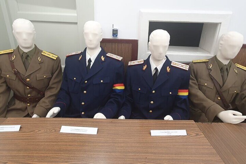 Four mannequins in military uniforms seated at a table with name cards. 3