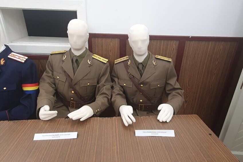 Two mannequins in military uniforms seated at a table with nameplates. 2