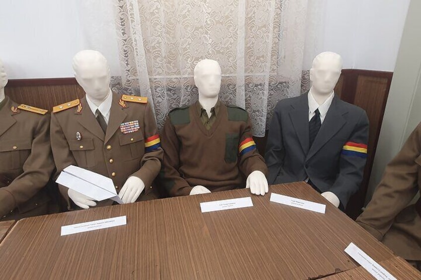 Three mannequins seated at a table with nameplates. 4