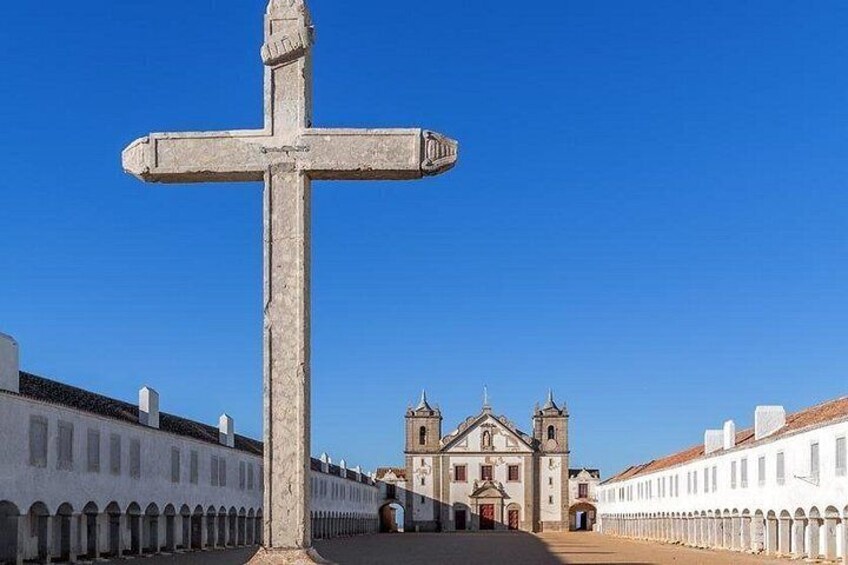 A large stone cross in the foreground with a church in the background. 3