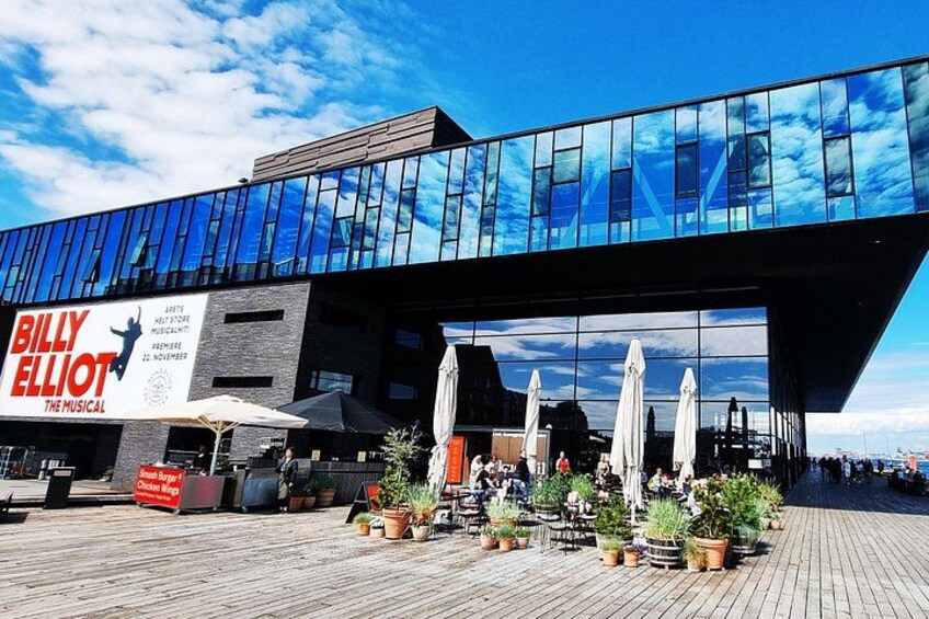 A modern building with a glass facade and a sign for 'Billy Elliot The Musical.' 2