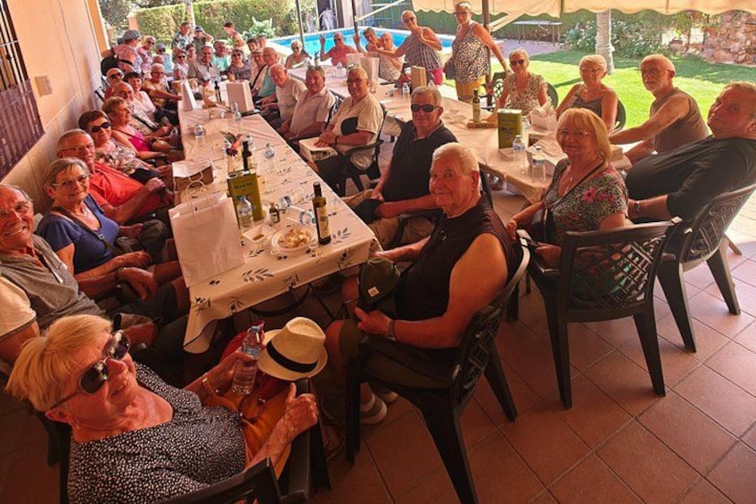 A group of people seated at a table with food and drinks, outdoors on a patio. 2