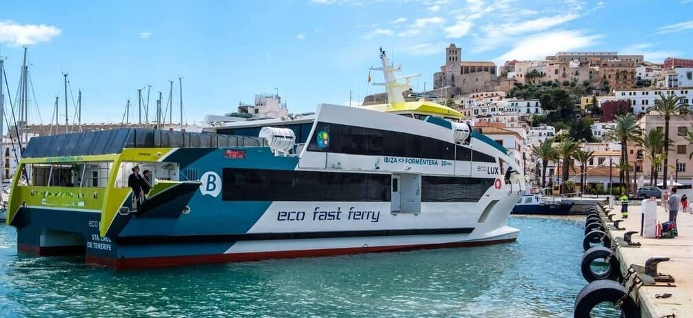 A ferry named 'eco fast ferry' docked at a marina with a cityscape in the background. 1
