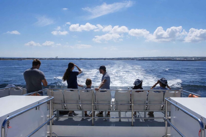 A group of people on a boat with a view of the open sea and distant shoreline. 4