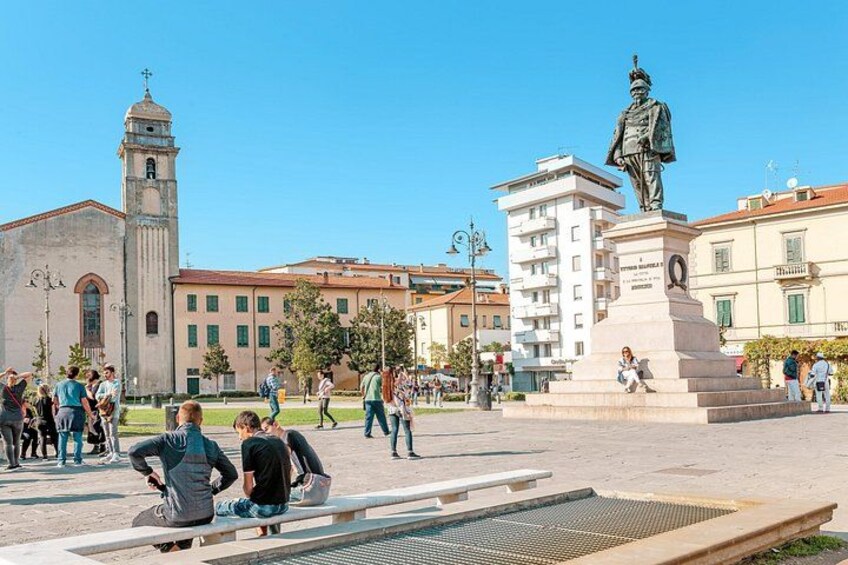 Una plaza pública con una estatua, una iglesia y edificios modernos. 1