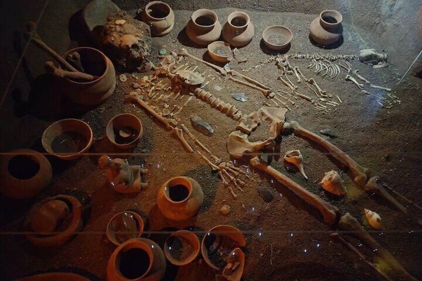 Pottery shards, broken pottery, and tools on a dirt floor. 3