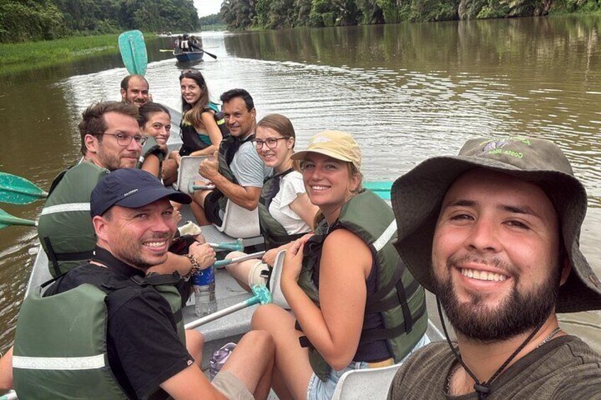Un grupo de personas en un bote con chalecos salvavidas y remos, navegando por un río tranquilo. 5