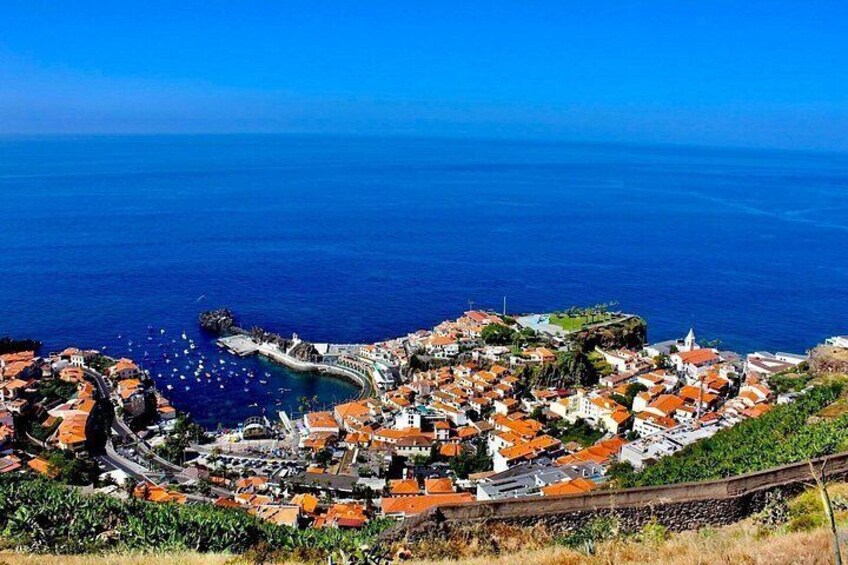 Un borgo costiero con edifici dai tetti rossi, una strada tortuosa e un mare cristallino. 1