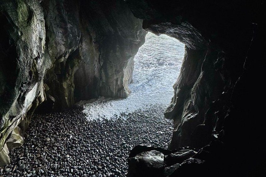 Una grotta con pavimento roccioso e un'apertura naturale che si apre su un corso d'acqua. 5