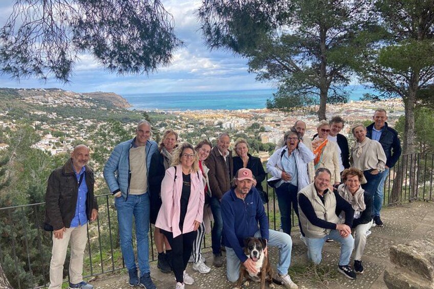 A group of people standing on a rocky outcrop overlooking a coastal town. 3