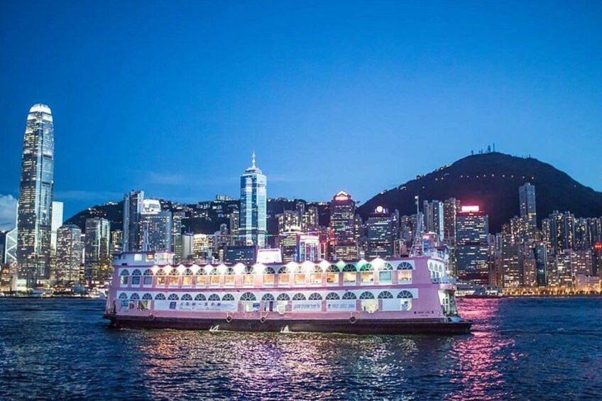 A ferry with multiple decks, a city skyline with tall buildings, and a hill in the background. 3
