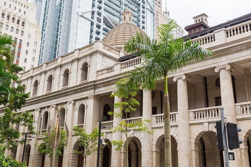 A historic building with classical architecture, including columns and arches, surrounded by modern high-rise buildings. 1