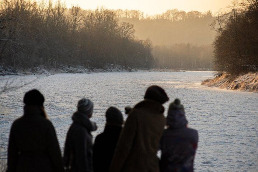 En gruppe mennesker går på en sti dækket af sne i et skovområde. 5